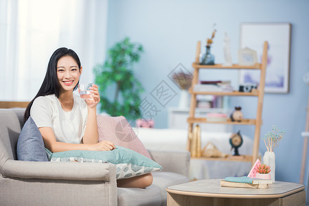 坐在沙发上的女孩女性坐在沙发上喝水背景