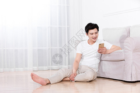 男性坐在地上靠着沙发休息图片