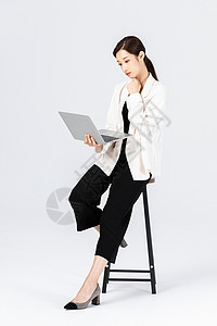 电脑椅图片坐在高脚椅上的商务女性看笔记本电脑背景