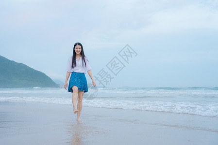 海浪上的美女深圳西冲沙滩上的少女玩水背景