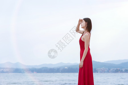 深圳较场尾海边礁石上的红衣少女眺望远方侧影高清图片