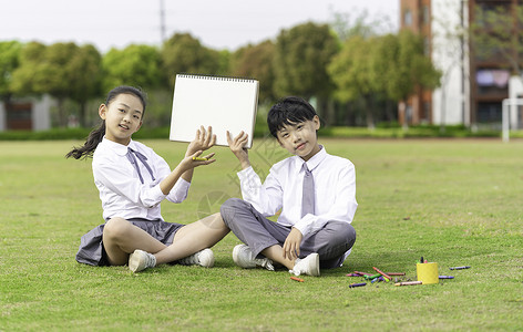 学生坐在草地上拿着画板图片