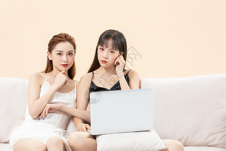 青年女闺蜜坐在沙发看电脑背景图片