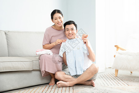 孕妇和丈夫在家收拾婴儿衣服幸福高清图片素材
