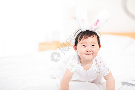 兔宝宝婴儿爬在床上玩耍背景