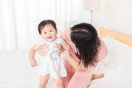 学走路宝宝妈妈扶着宝宝在床上走路背景