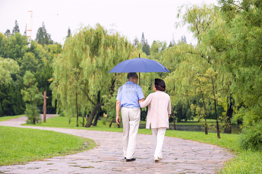 老年夫妇在公园雨中漫步背影