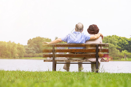 人生活老年夫妇坐在公园长椅背影背景
