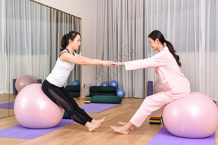 产后恢复中心产妇和教练一起练习瑜伽球背景