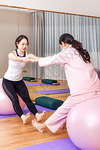 产妇和教练一起练习瑜伽球背景图片