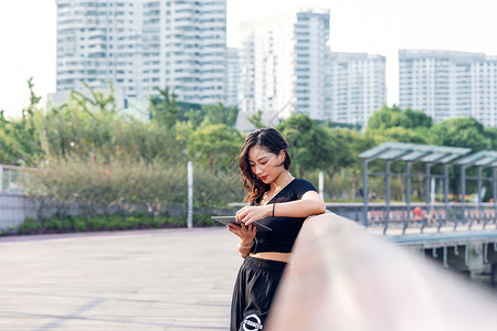 户外女性玩手机背景图片