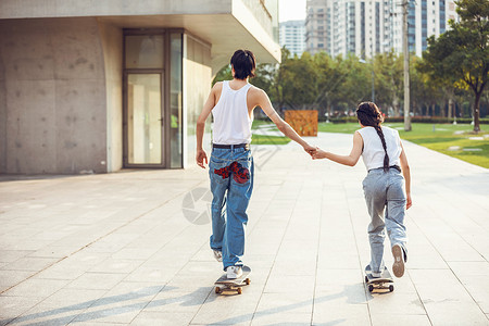 极限运动女情侣户外玩滑板背影背景