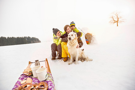 戴狗帽子男孩父母和儿子在雪地里抱着狗背景
