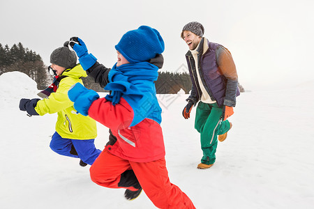 男人和两个男孩在雪地里奔跑图片