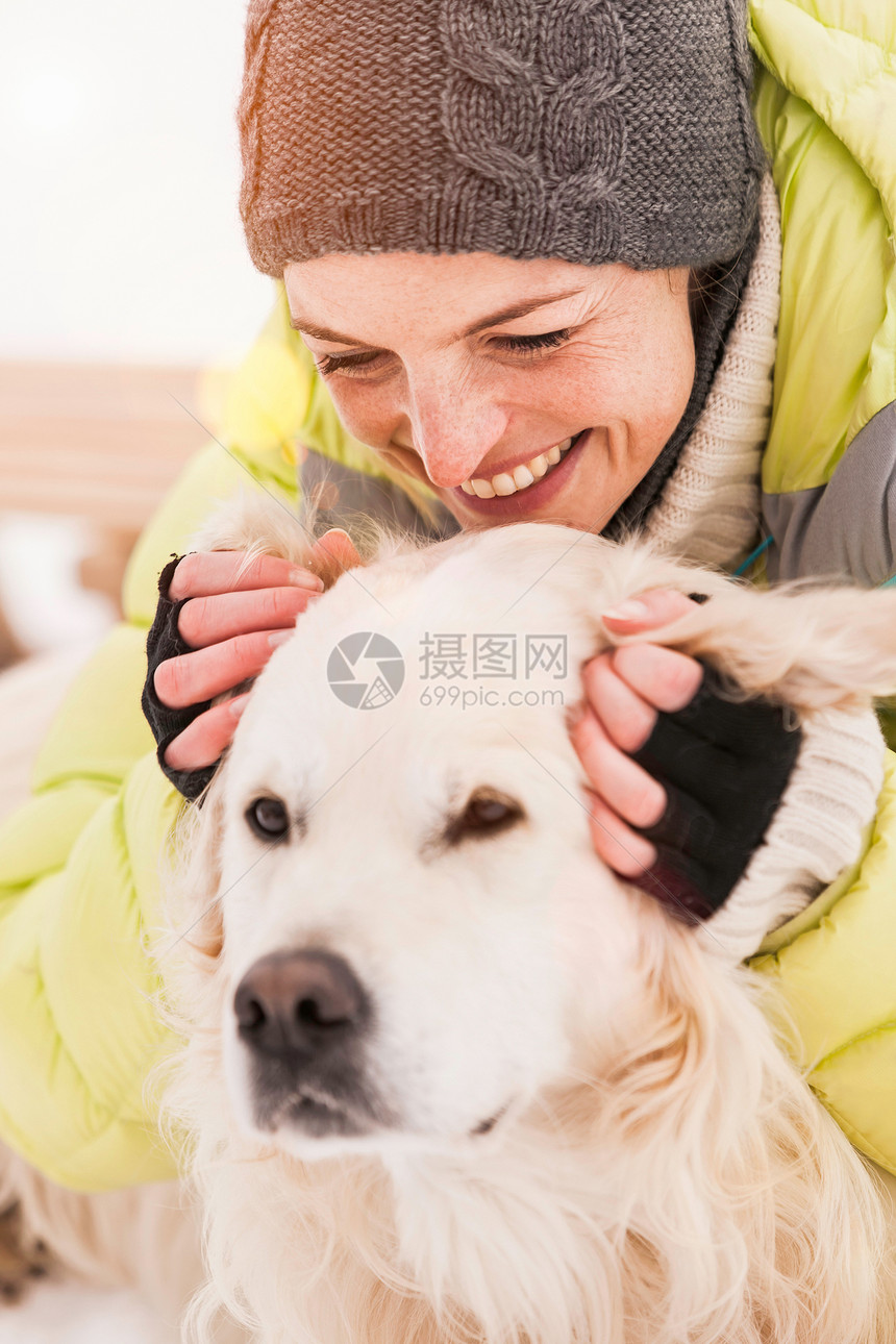 戴针织帽的女人抚摸狗图片