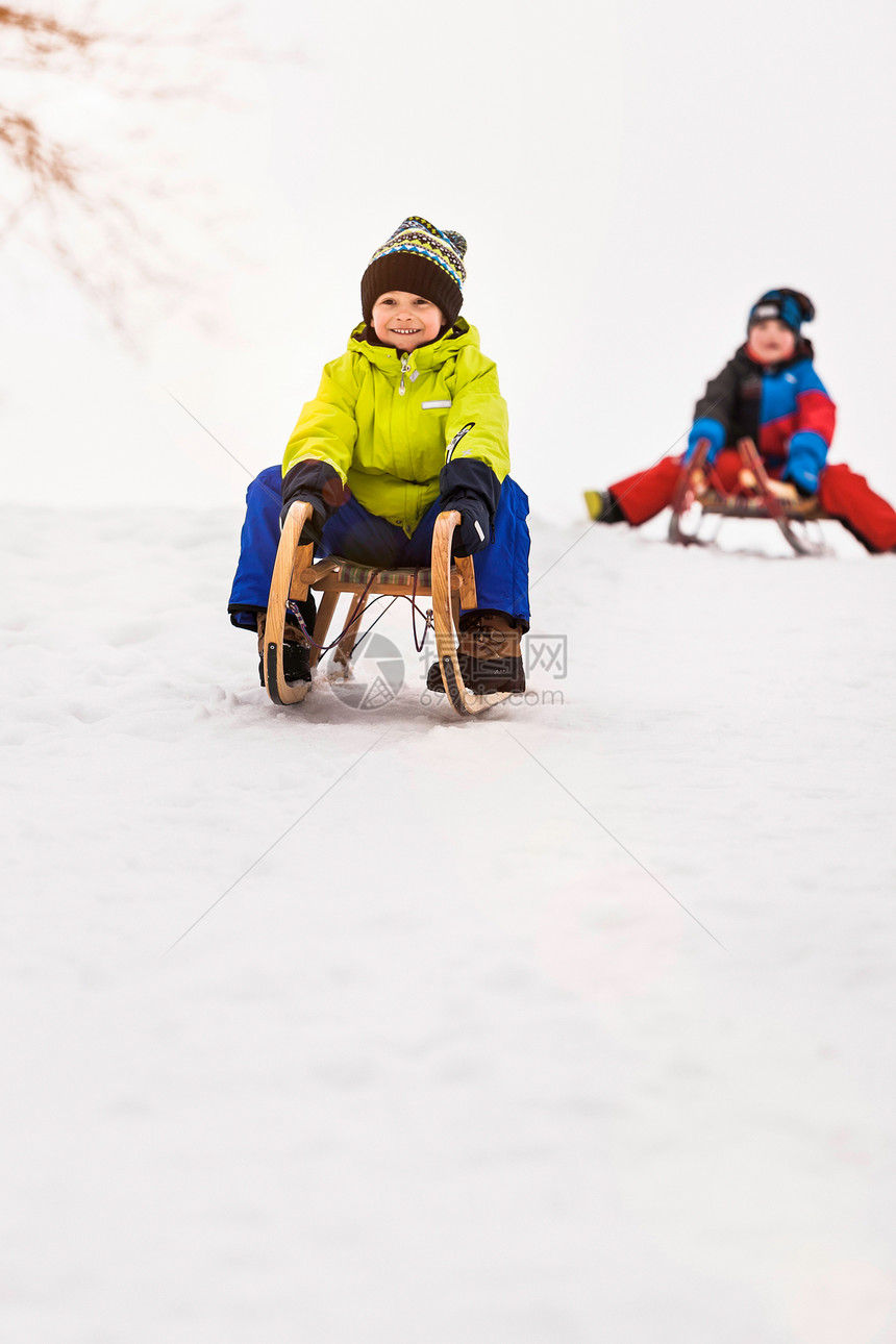 两个男孩在雪地里滑雪橇图片