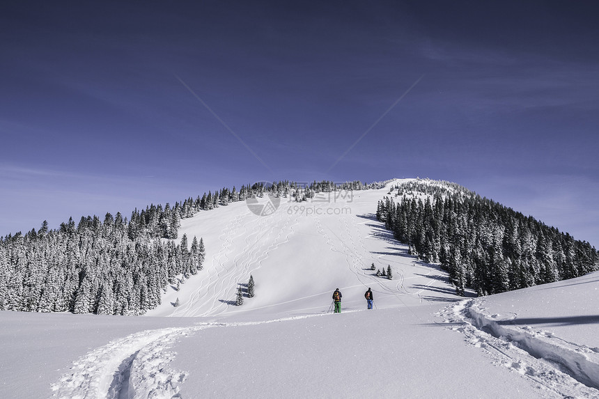 两名男性滑雪者在德国斯皮津西冰雪覆盖的山上行走的远视图图片