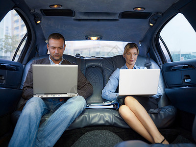 坐在豪华轿车里带着笔记本电脑的商人图片