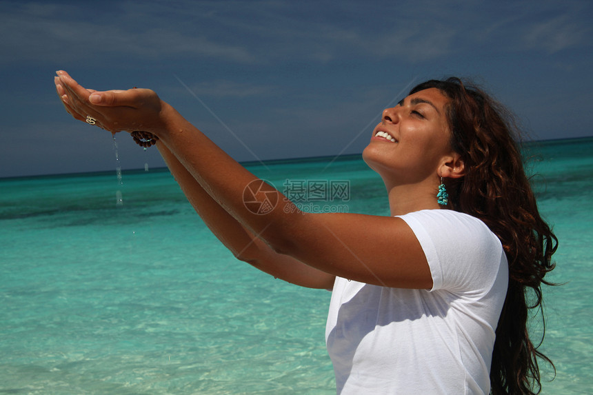 巴哈马，手放杯水的海滩上的年轻女子图片
