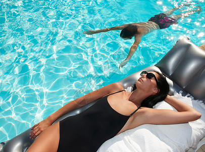 日光浴素材泳池晒日光浴的女子背景