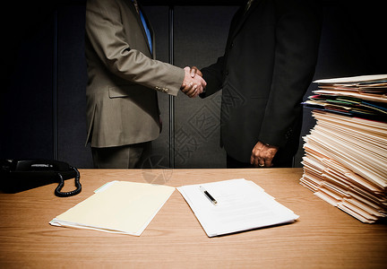 外国人室内两个商人在办公桌上握手背景