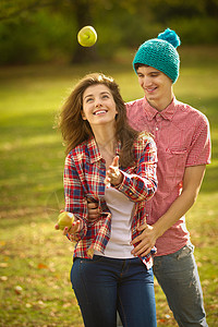 玩杂耍人一对年轻夫妇在公园里玩苹果杂耍背景