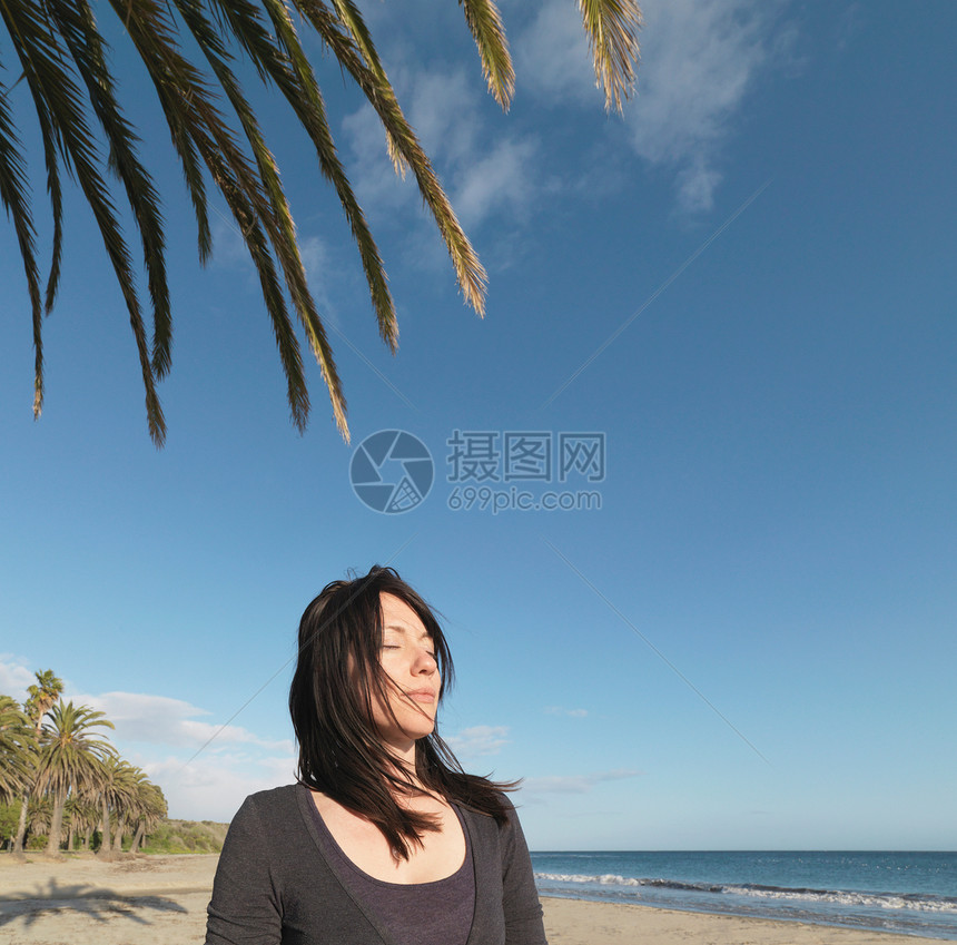女人在沙滩上放松，闭上眼睛图片