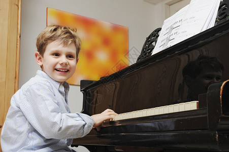 在客厅弹钢琴的男孩外国儿童高清图片素材