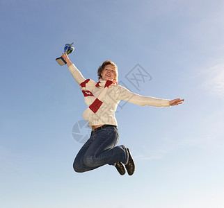 女子跳跃，手持奖杯图片