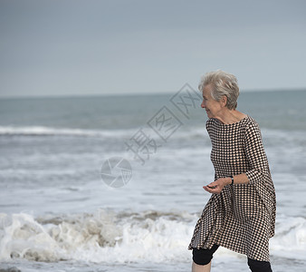 美国加利福尼亚州达纳角海滩海浪中奔跑的资深女性图片