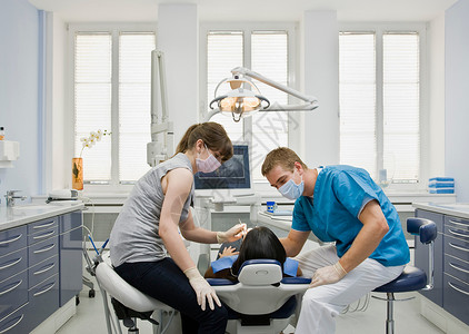 牙医椅带病人和助手的牙医背景