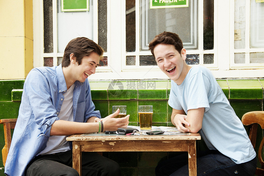 微笑的男人在咖啡馆喝啤酒图片
