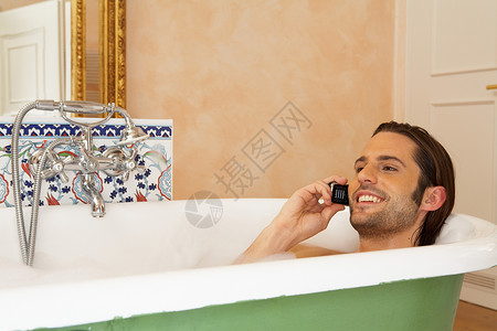 拿着手机在浴缸里微笑的年轻人图片