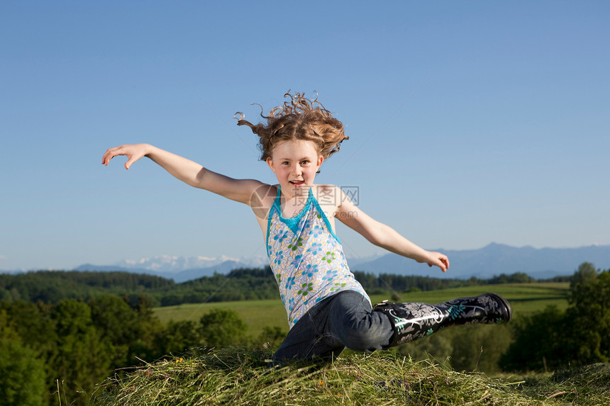 女孩在草地上跳跃图片