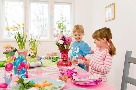 男孩和女孩在复活节餐桌上玩耍高清图片