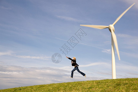 在风力发电机前跳跃的人图片