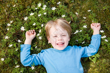 小孩拿花躺在草地上笑的男孩背景