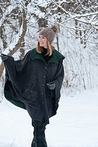穿厚斗篷在雪地里行走的女人高清图片