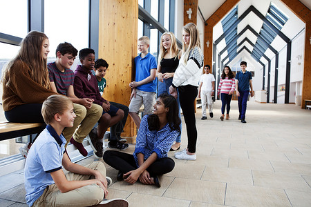 英国孩子坐在走廊里聊天的一群十几岁的小学生背景