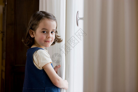 站在窗帘前的小女孩图片