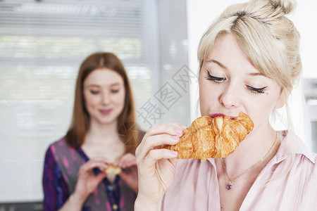 吃牛角包的年轻妇女图片