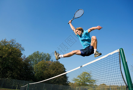 年轻人用网球拍跳网图片