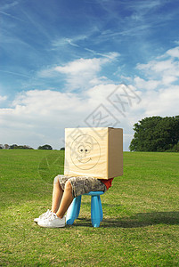 男孩坐在凳子上，盒子放在头上背景图片