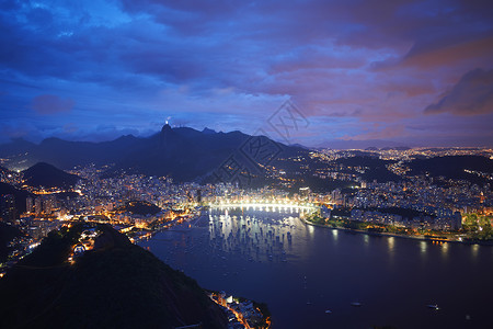 里约热内卢基督从巴西里约热内卢的Sugar Loaf Mountain夜间俯瞰港口和海岸背景