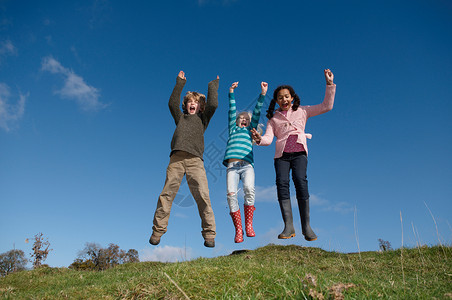 三个孩子在山上跳人高清图片素材