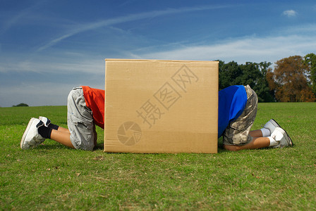 两个男孩爬进箱子里草地高清图片素材