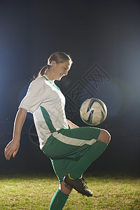 女子足球运动员膝上弹跳球背景图片