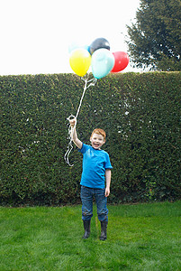微笑的男孩拿着一堆气球图片