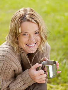 拿着杯子的女人在户外微笑背景图片