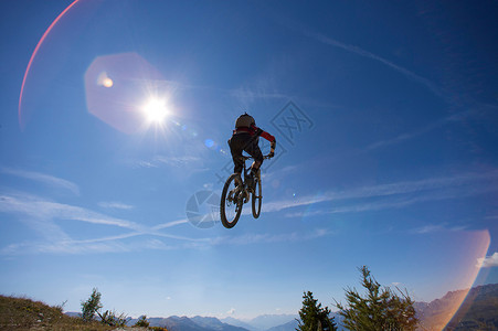 山地自行车手跃过头顶背景图片